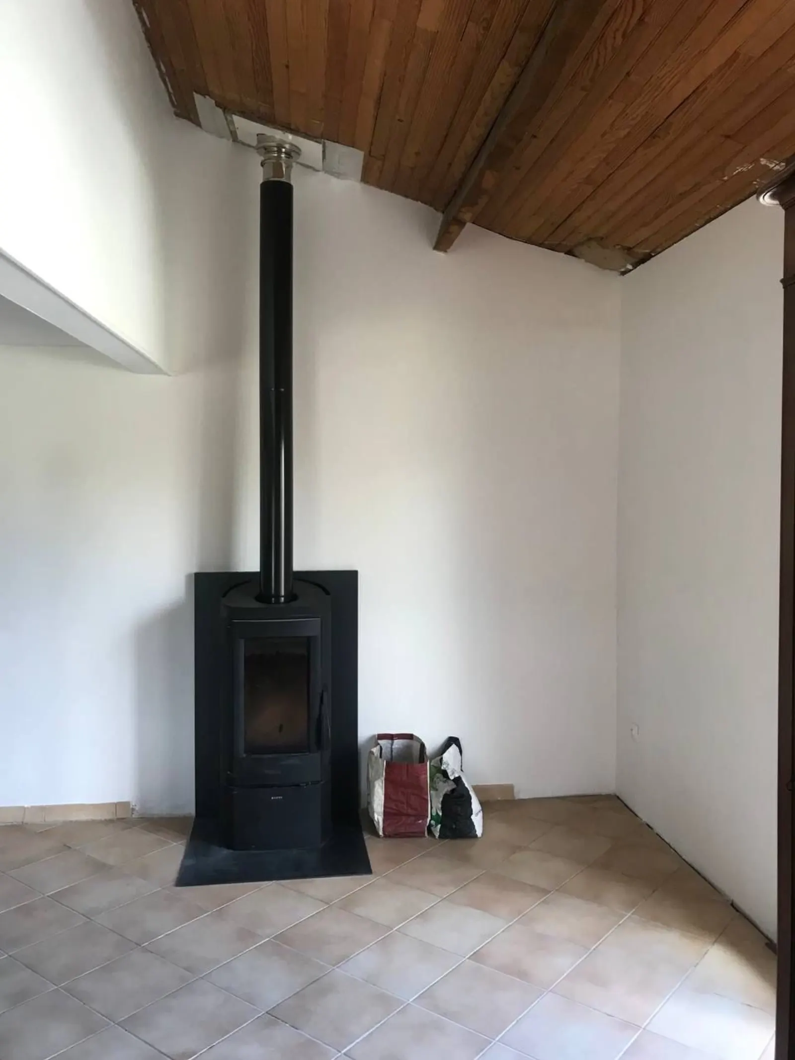 Pièce de vie rénovée avec poêle — peinture blanche unie par SmatiProServices